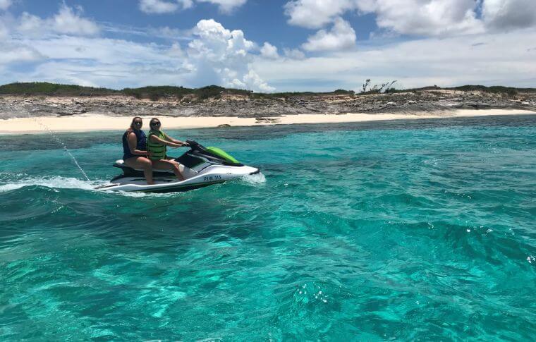 People sit on jet ski near the shore.